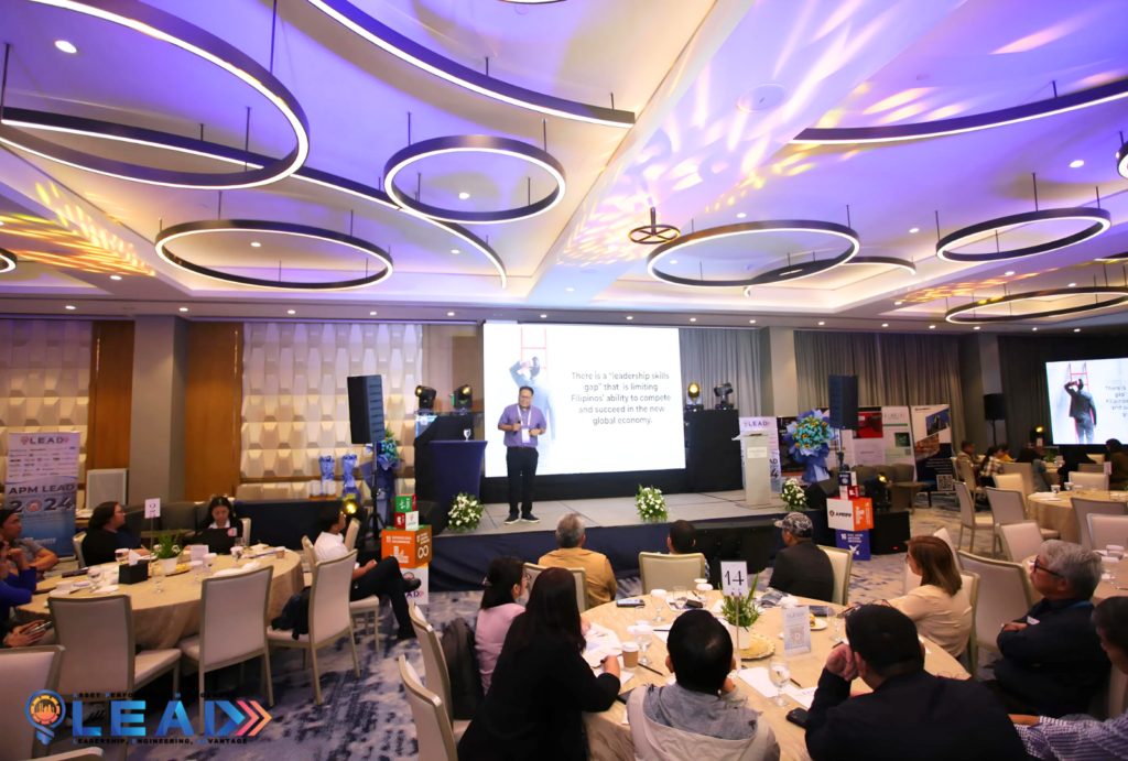 Richard Caballero presenting on stage at the APM LEAD 2024 conference, with a slide reading "There is a leadership skills gap"
