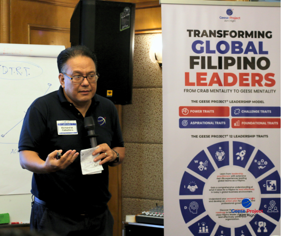 Richard Caballero presenting beside a "Transforming Global Filipino Leaders" banner at the July workshop